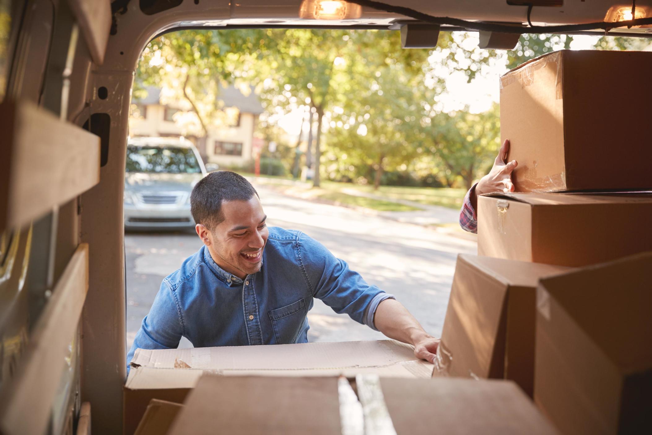 Smiling man removing boxes from back of moving van