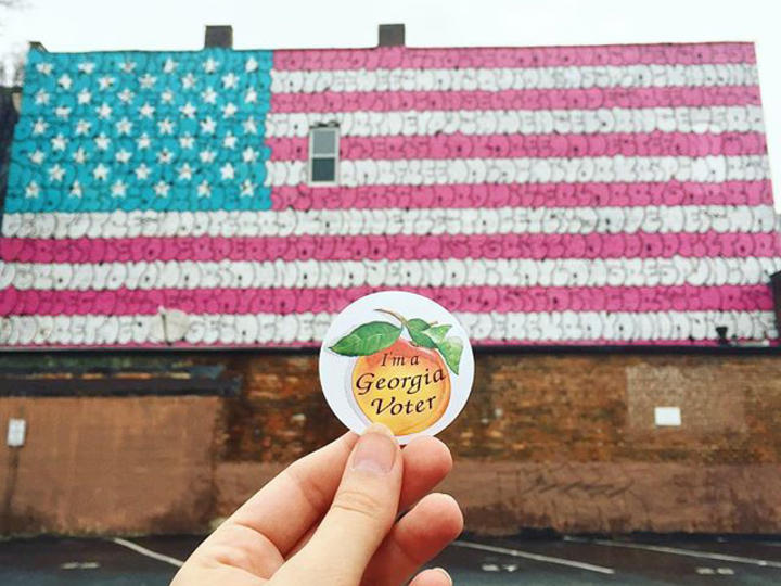 Georgia voter sticker in front of American flag mural
