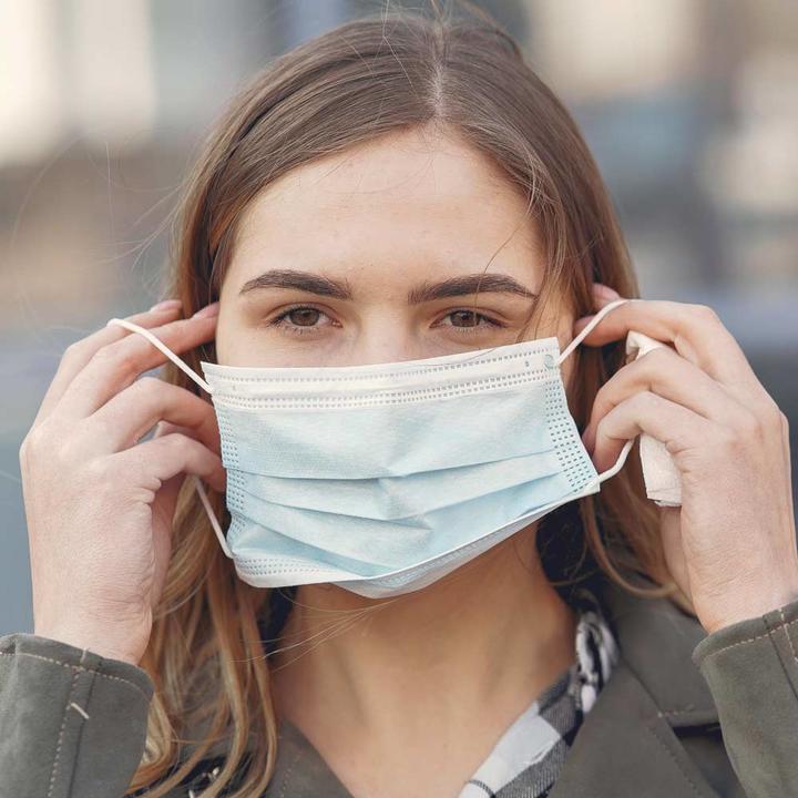 Woman putting on a disposable face mask