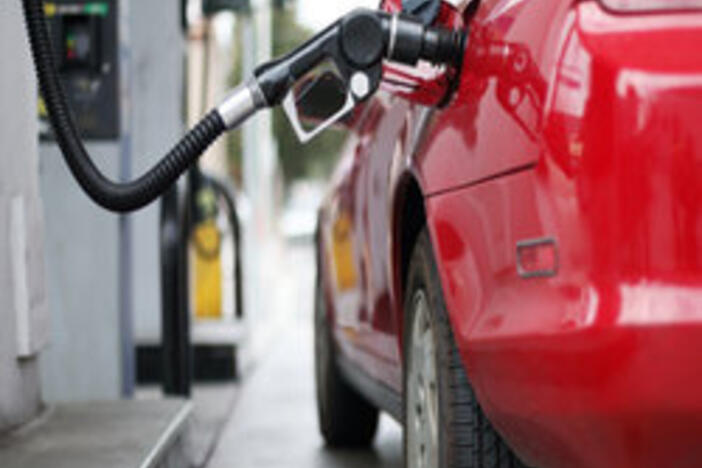 Red car filling up at the gas pump.